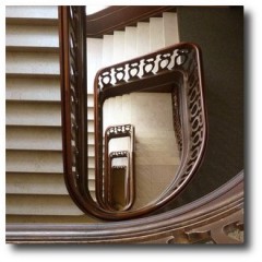 Treppenhausreinigung Bremen: Der Blick in das Treppenauge eines alten Treppenhauses zeigt schönes geschnitztes Treppengeländer und einen Handlauf aus Holz.